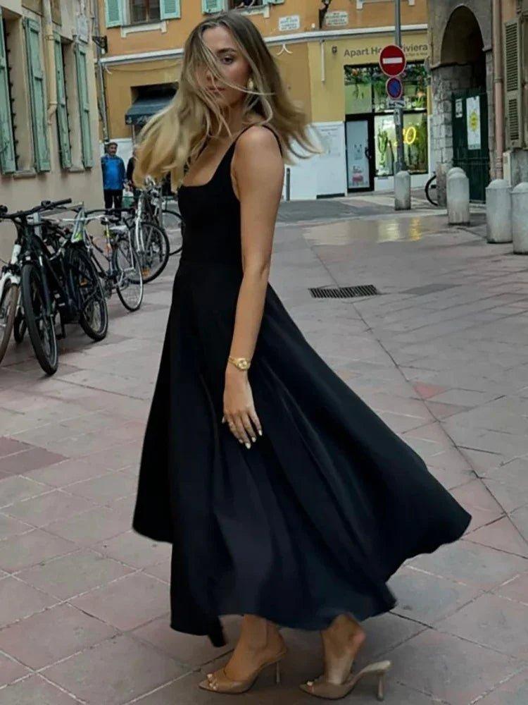 Woman in elegant black midi dress walking on city street, fashion style