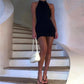 Woman in black halter mini dress with white bag on spiral staircase, fashion outfit