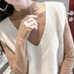 Woman wearing elegant lace long sleeve top under cream V-neck sweater, fashion layering outfit