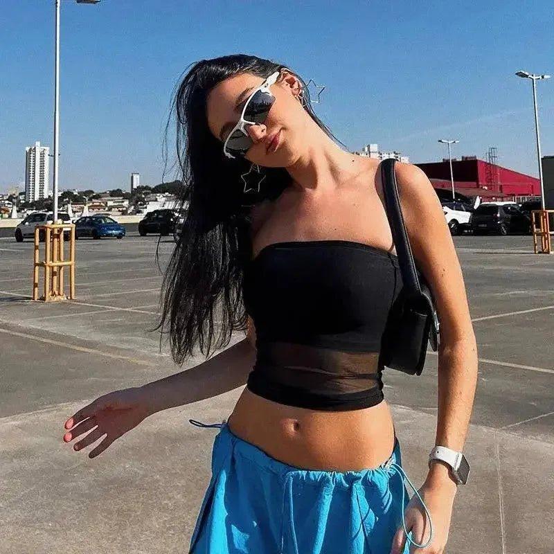 Woman in black crop top and blue skirt, wearing star sunglasses, outdoor fashion look