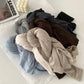 Soft women's fashion tops in neutral tones, styled with Jil Sander magazine and decor