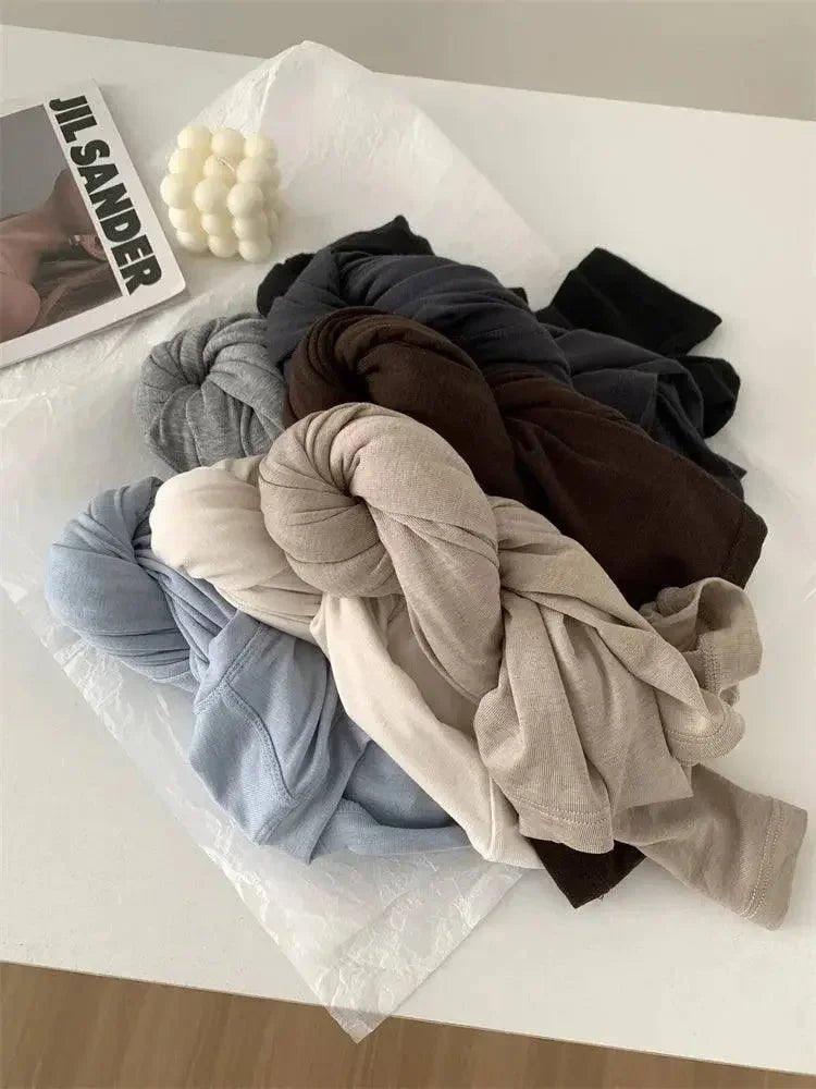 Soft women's fashion tops in neutral tones, styled with Jil Sander magazine and decor