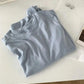 Light blue women's fashion t-shirt with minimalist styling, paired with hoop earrings and a book