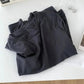 Black women's fashion t-shirt with round neck, styled on white surface with book and earrings