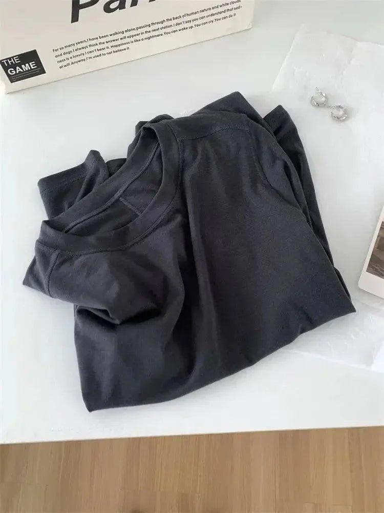 Black women's fashion t-shirt with round neck, styled on white surface with book and earrings