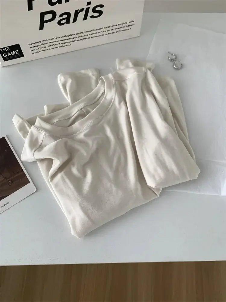 Cream women's long sleeve top styled with Paris magazine and earrings, minimalist fashion