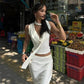 Woman in white wrap top and skirt at outdoor fruit market, stylish streetwear fashion