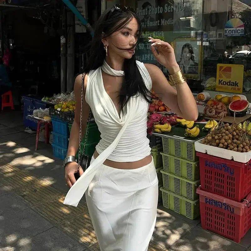 Woman in white wrap top and skirt at outdoor fruit market, stylish streetwear fashion