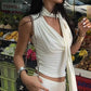 Woman in white ruched crop top with halter neck, shopping at outdoor fruit market, stylish summer fashion