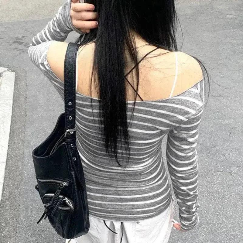 Woman wearing striped off-shoulder long sleeve top with black crossback detail and leather shoulder bag