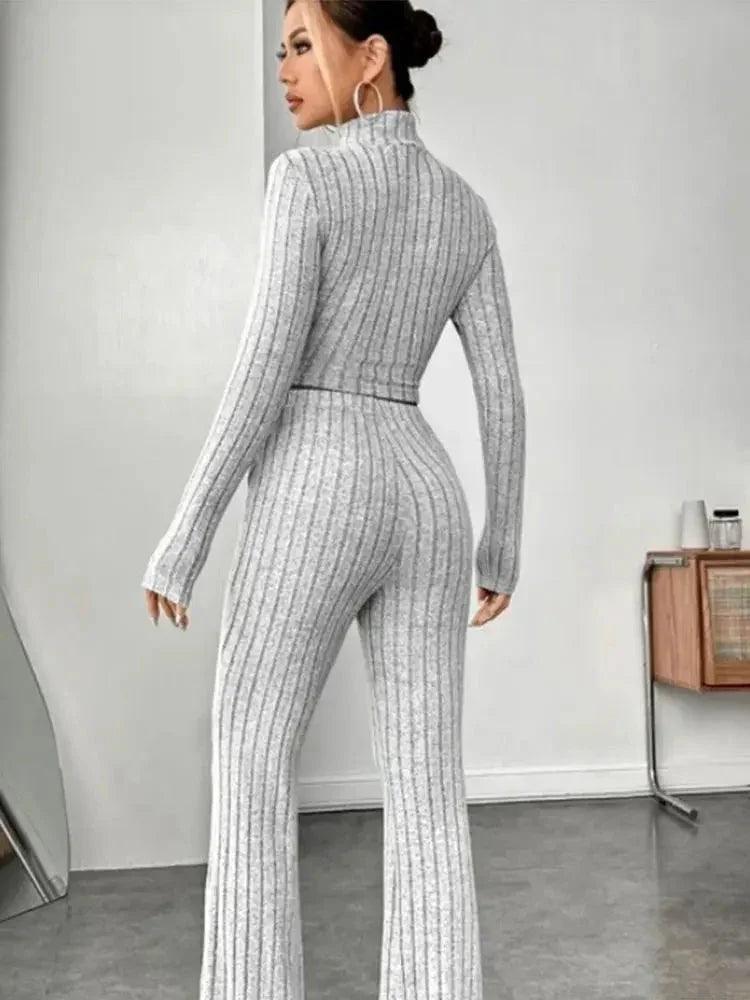 Woman in gray ribbed knit jumpsuit with long sleeves and flared legs, fashion outfit