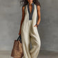 Woman in cream sleeveless jumpsuit with black embroidery, carrying woven tote bag, stylish summer fashion