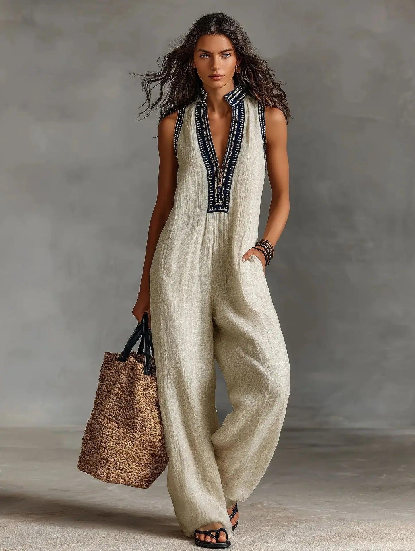 Woman in cream sleeveless jumpsuit with black embroidery, carrying woven tote bag, stylish summer fashion