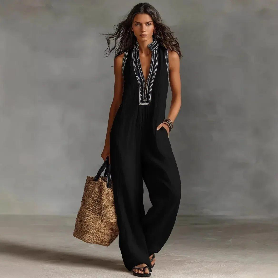 Woman in black sleeveless jumpsuit with white embroidery, carrying straw tote bag, fashion outfit
