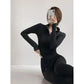Woman in black long sleeve zip-up top and leggings, posing with phone, fashion activewear