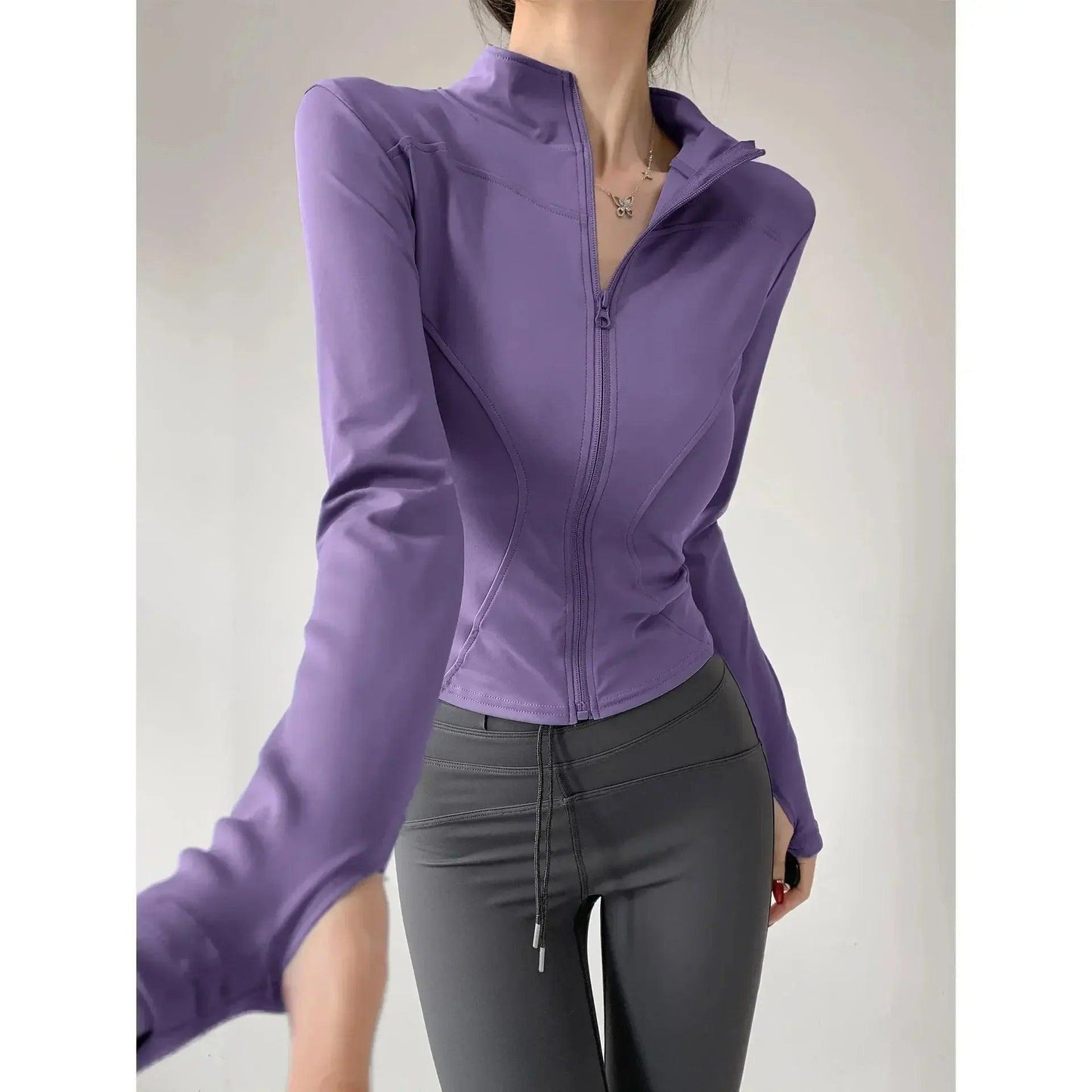 Purple zip-up fitness jacket with long sleeves, styled with gray leggings for women's activewear.