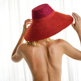 Woman wearing wide-brimmed red straw hat, summer fashion accessory for beach or sun protection