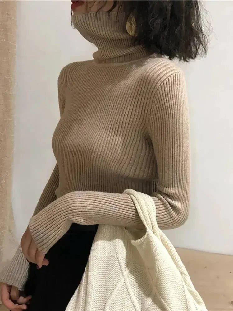 Woman wearing beige ribbed turtleneck sweater with cozy knit texture, styled with black pants and cream tote bag