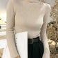 Cream ribbed turtleneck sweater for women, paired with black high-waist pants and belt, stylish office look