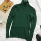 Green turtleneck sweater with cozy aesthetic, styled with tea cup and floral card on white bedding
