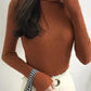 Rust ribbed turtleneck sweater with long sleeves, paired with white pants and checkered scarf