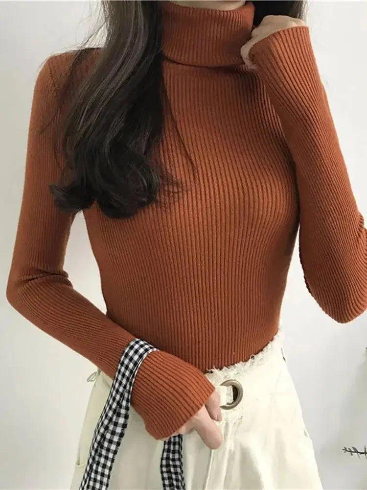 Rust ribbed turtleneck sweater with long sleeves, paired with white pants and checkered scarf