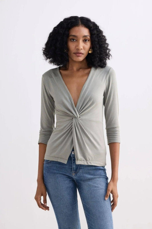 Woman wearing olive green twist-front long sleeve top with jeans, stylish fashion outfit