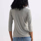 Woman wearing olive green ribbed 3/4 sleeve top with blue jeans, back view
