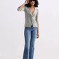 Woman in stylish green twist-front top, blue jeans, and loafers, adjusting sunglasses for chic fashion look