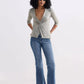 Woman in olive twist-front top, blue flare jeans, and beige loafers, stylish fashion outfit