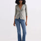 Woman wearing olive twist-front top, blue flared jeans, and beige loafers for casual fashion look