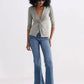 Woman in olive twist-front top, blue flare jeans, and beige loafers — stylish women's fashion outfit
