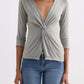 Woman wearing olive green twist-front top with 3/4 sleeves and blue jeans, fashion outfit
