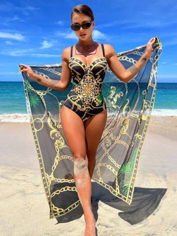 Woman in black gold patterned one-piece swimsuit with matching beach cover-up on sandy shore