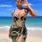 Woman in stylish black and gold chain print beach dress, sunglasses, ocean backdrop