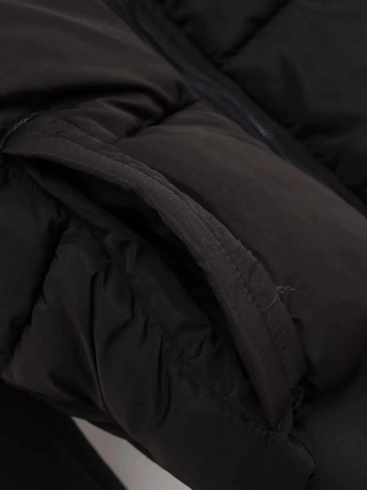 Black puffer jacket close-up showing quilted texture and zipper detail, women's fashion outerwear