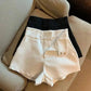 White and black high-waisted fashion shorts with button details, styled on a cozy sofa