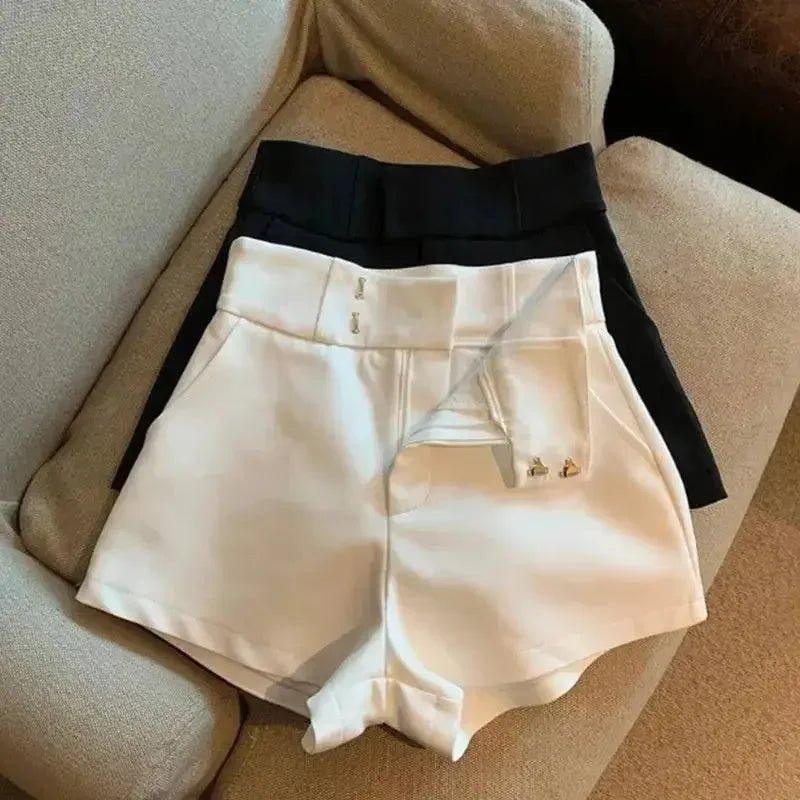 White and black high-waisted fashion shorts with button details, styled on a cozy sofa