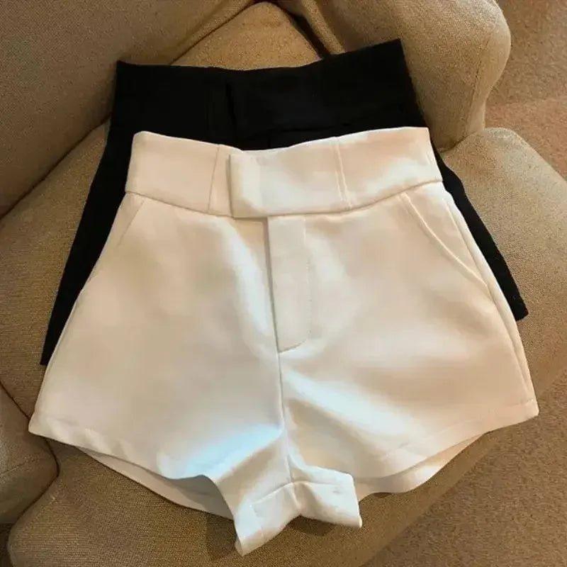 White and black high-waisted women's fashion shorts on beige couch