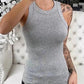 Woman wearing gray sleeveless tank top, casual fashion, home selfie with tattooed arm