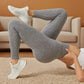 Woman in gray ribbed leggings and white sneakers, posing on carpeted floor for fashion look