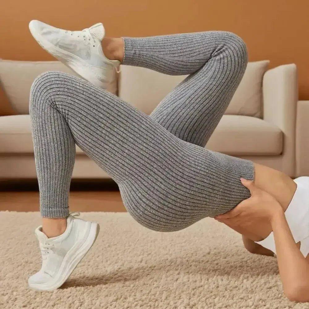 Woman in gray ribbed leggings and white sneakers, posing on carpeted floor for fashion look