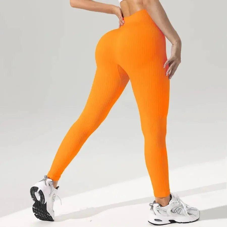 Bright orange ribbed high-waist leggings for women, paired with white sneakers, perfect for fitness and fashion.