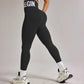 Black high-waisted leggings with 'BEGIN' print, white sports bra, and chunky sneakers for women's fitness fashion