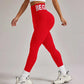Woman in red high-waist leggings with 'BEGIN' waistband, white sports bra, and chunky sneakers