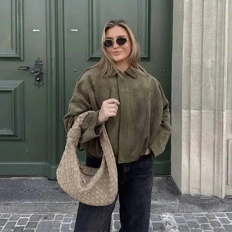 Woman in olive green shirt, sunglasses, and woven bag, street style fashion