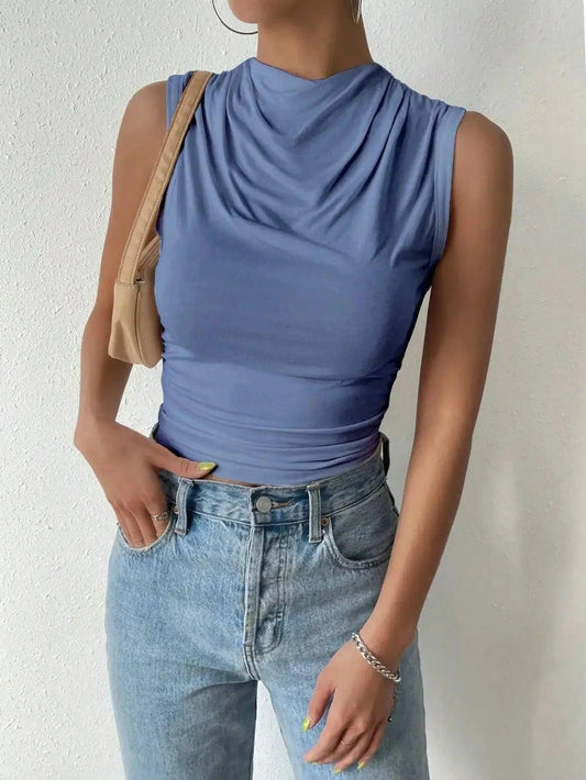 Woman wearing blue sleeveless cowl neck top with high waist jeans, stylish fashion outfit