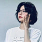 Woman with short black hair wearing glasses and white graphic tee, fashion style
