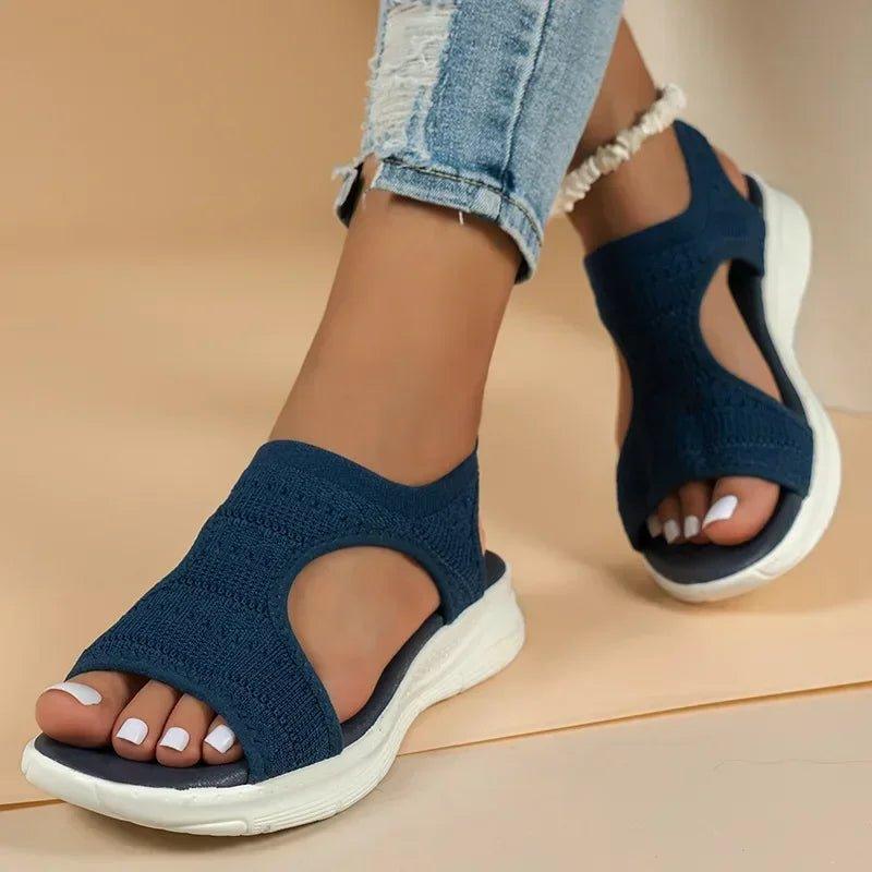 Women's navy blue knit sandals with white soles, paired with ripped denim jeans for casual fashion