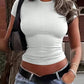 Woman wearing ribbed white crop top, low-rise jeans, and black belt, casual outdoor fashion